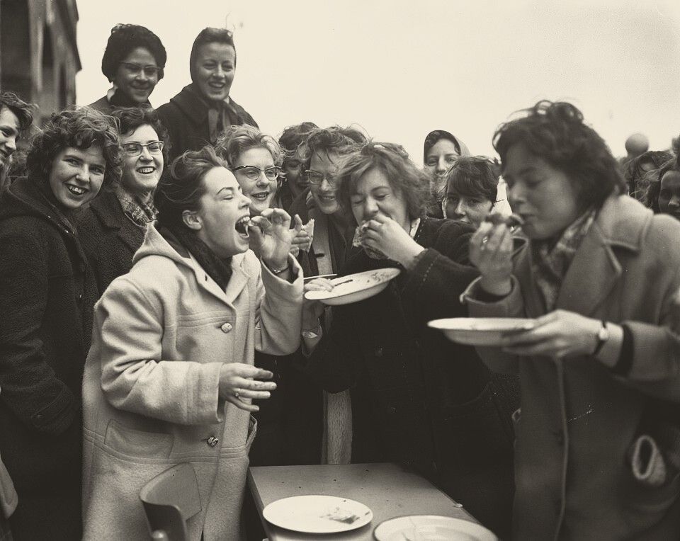 Students eating pancakes during a race, 1960